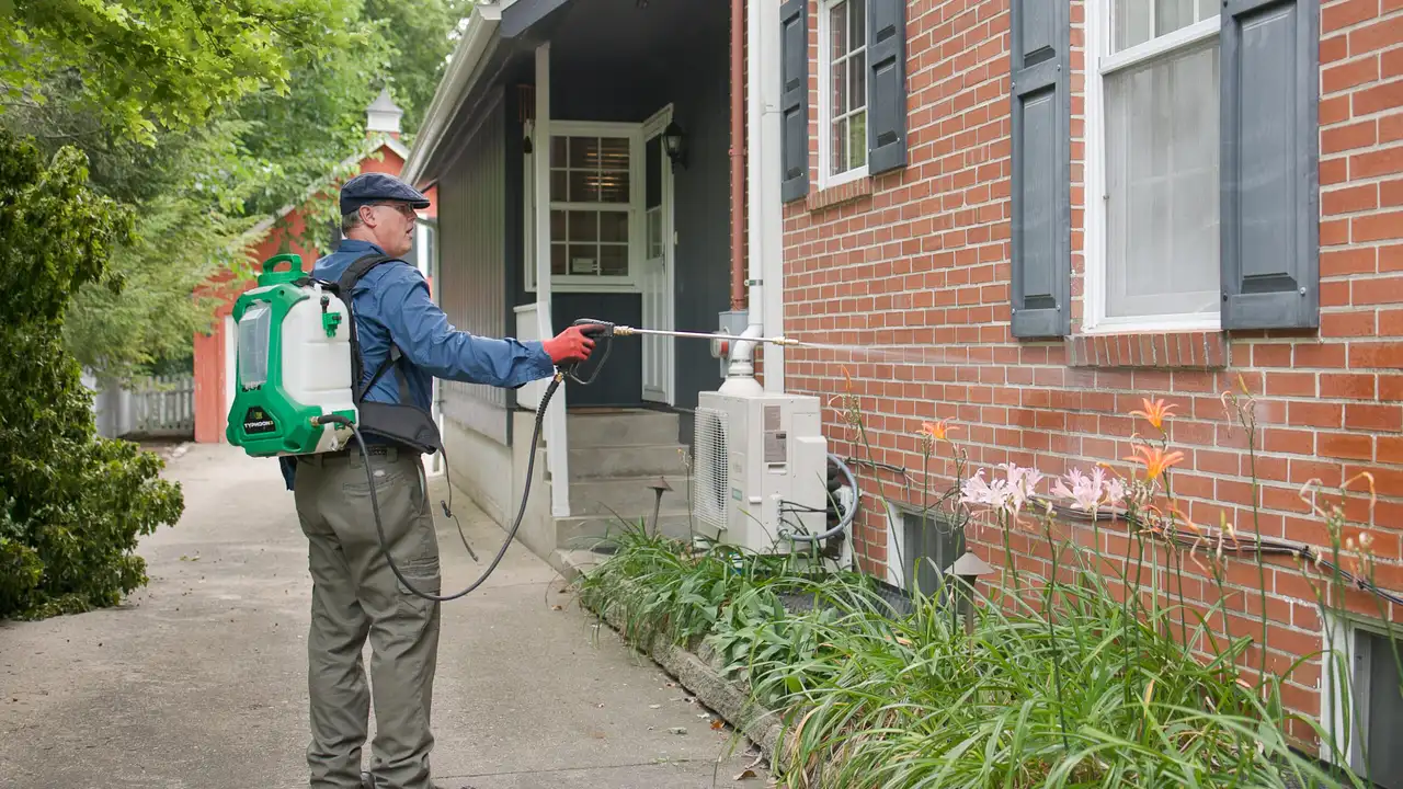 Bug Off technician treating a home exterior at the foundation line